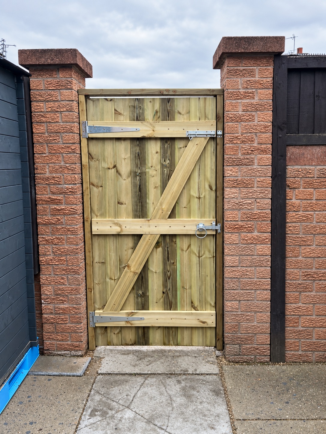 Ledge and brace timber gate fitted between two brick pillars