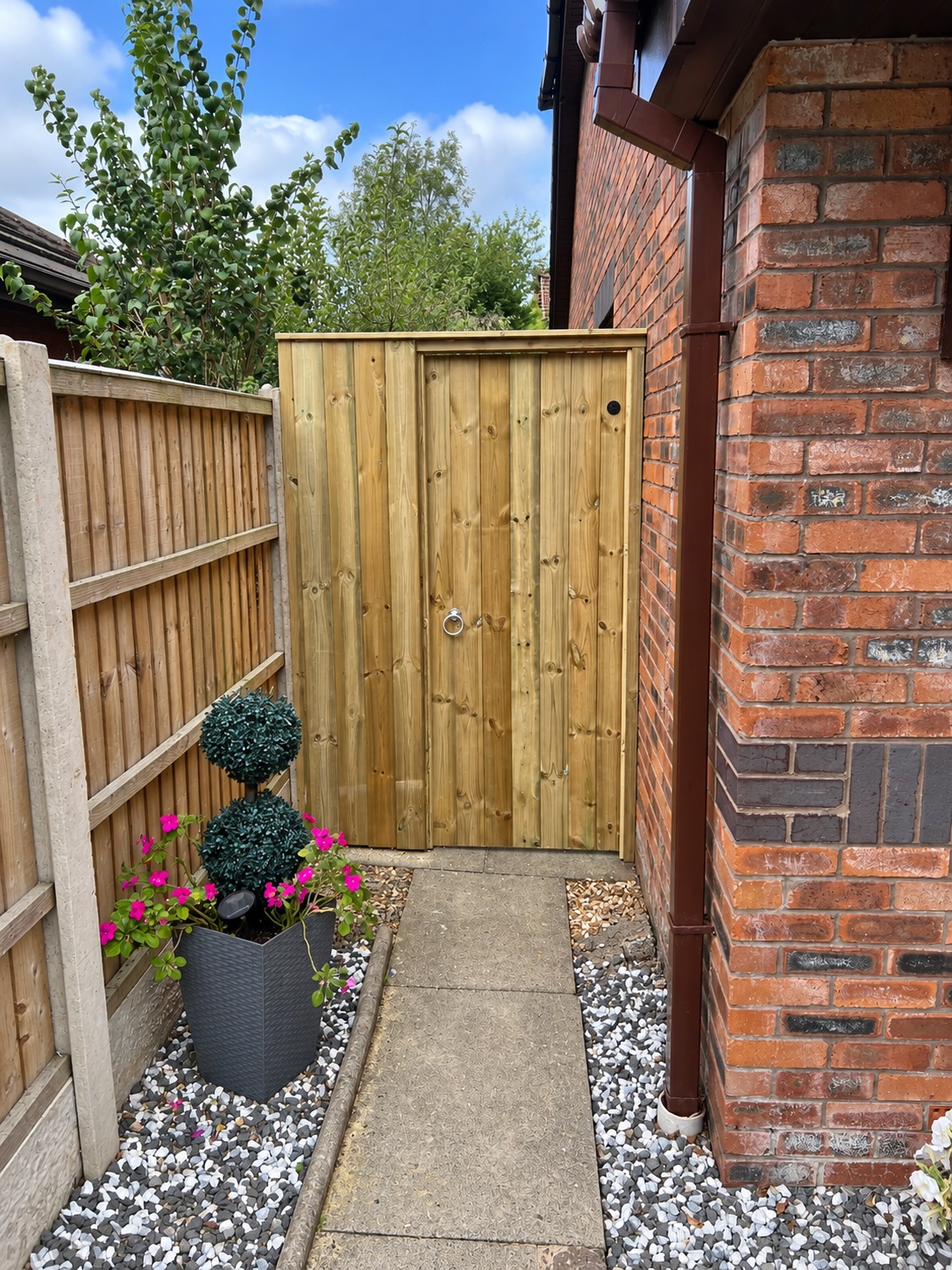 Natural timber garden passage gate fitted beside a brick house