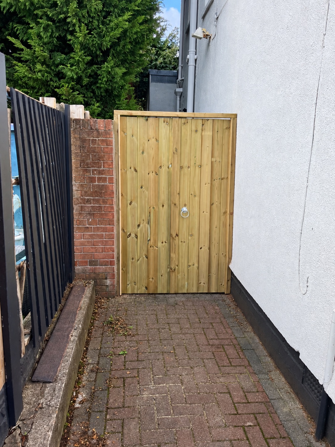 Natural timber gate closing a narrow side passage